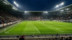 Verlicht voetbalstadion met groen grasveld tijdens een avondwedstrijd
