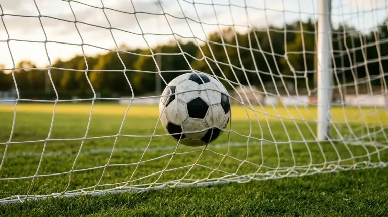 Voetbal in het doelnet van een voetbalveld na een doelpunt